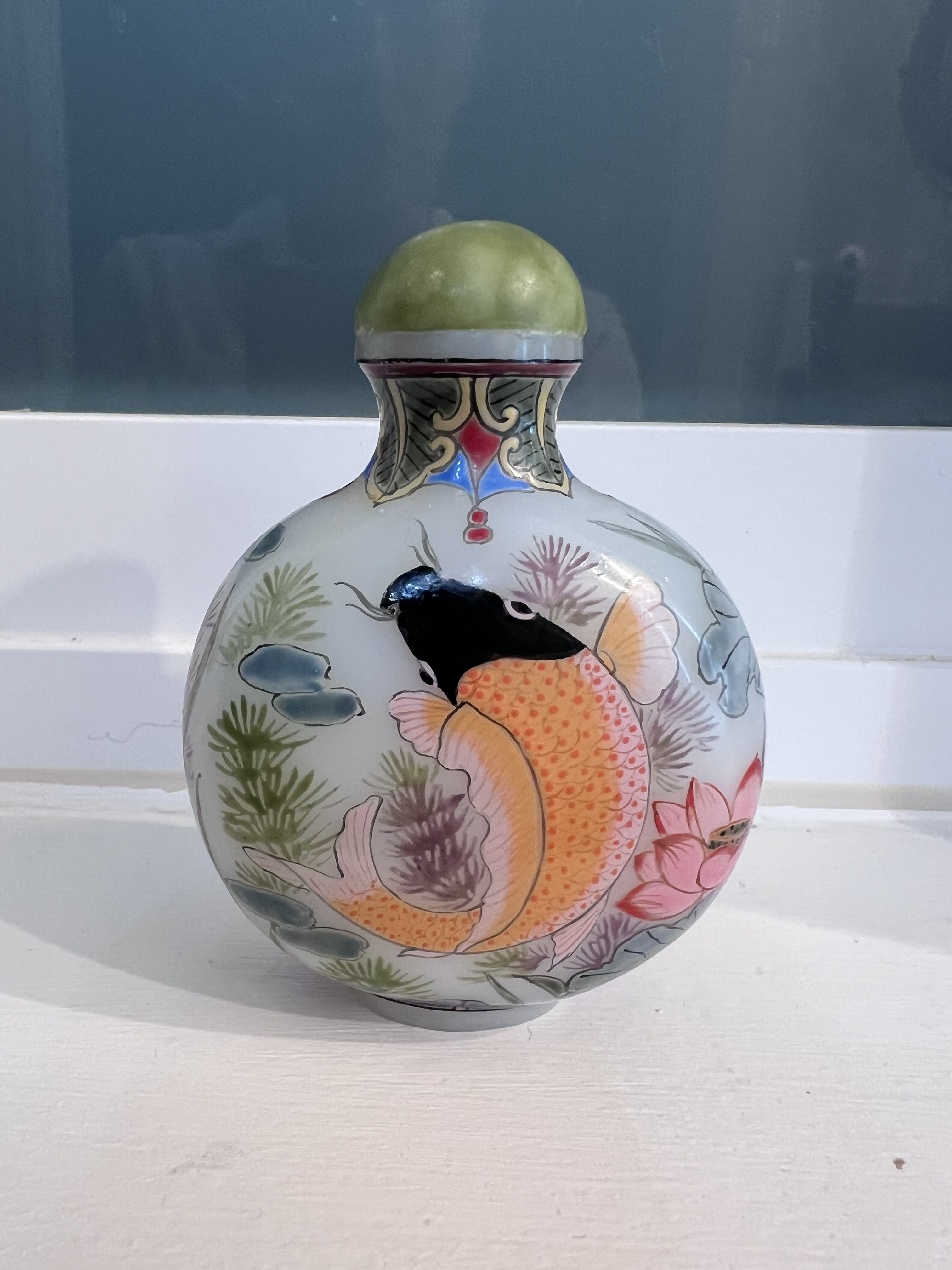 Chinese enameled glass snuff bottle featuring a hand-painted koi or goldfish design and a green stopper